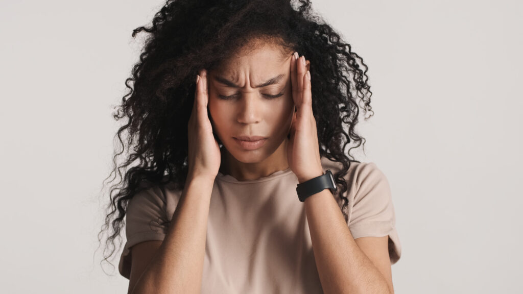 Ansiedade e estresse: sinais de alerta e quando marcar consulta presencial 1 upset dark fluffy haired african american woman massaging temples feeling headache white background pain head Central de Consultas | Clínica Popular