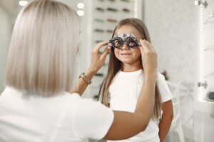 child eye test eye exam little girl having eye check up with phoropter doctor performs eye test child Central de Consultas | Clínica Popular