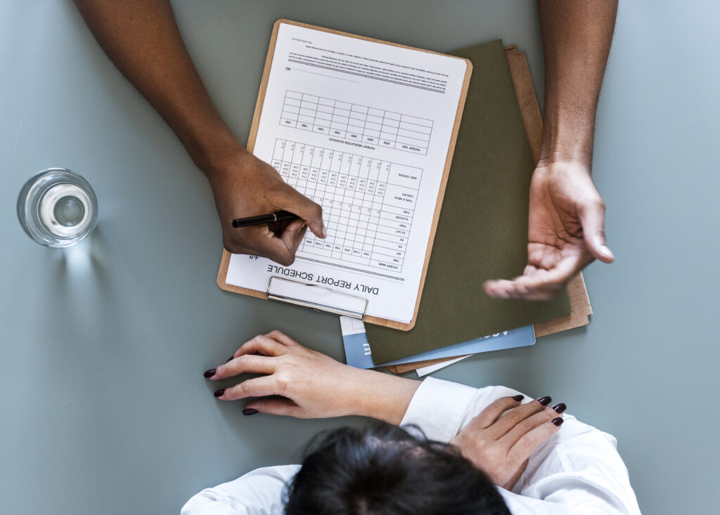 aerial view doctor writing patient daily report checklist Central de Consultas | Clínica Popular