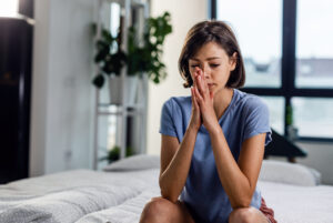 pensive woman with hands clasped sitting bed thinking something Central de Consultas | Clínica Popular